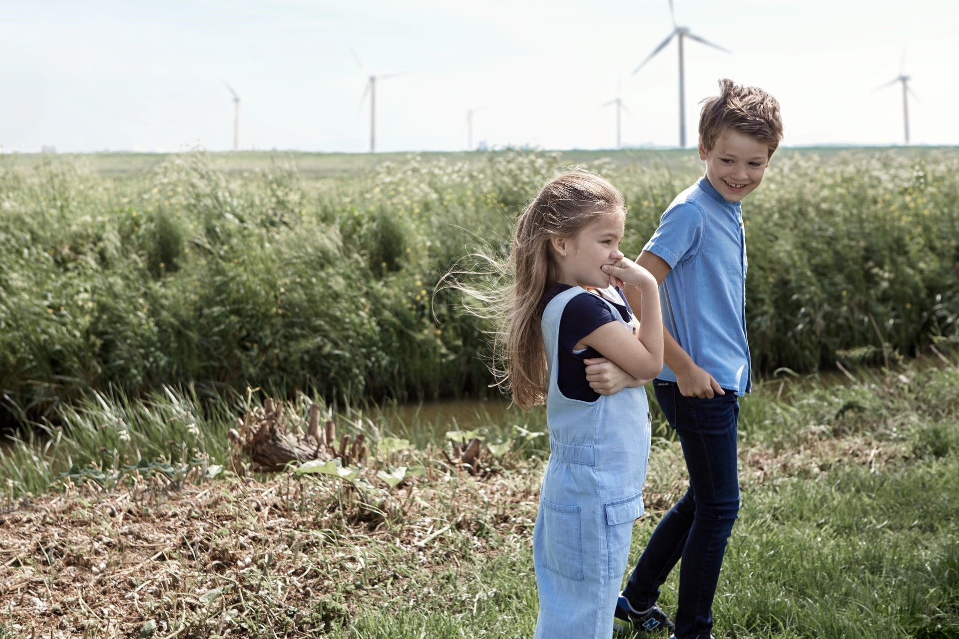 Meisje en jongen staat buiten voor windmolens