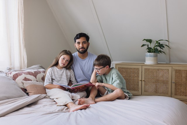 Man leest zijn kinderen voor op bed | Vattenfall