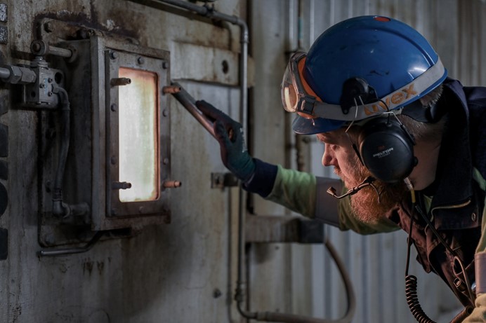 Medewerker afvalenergiecentrale kijkt in de verbrandingsoven