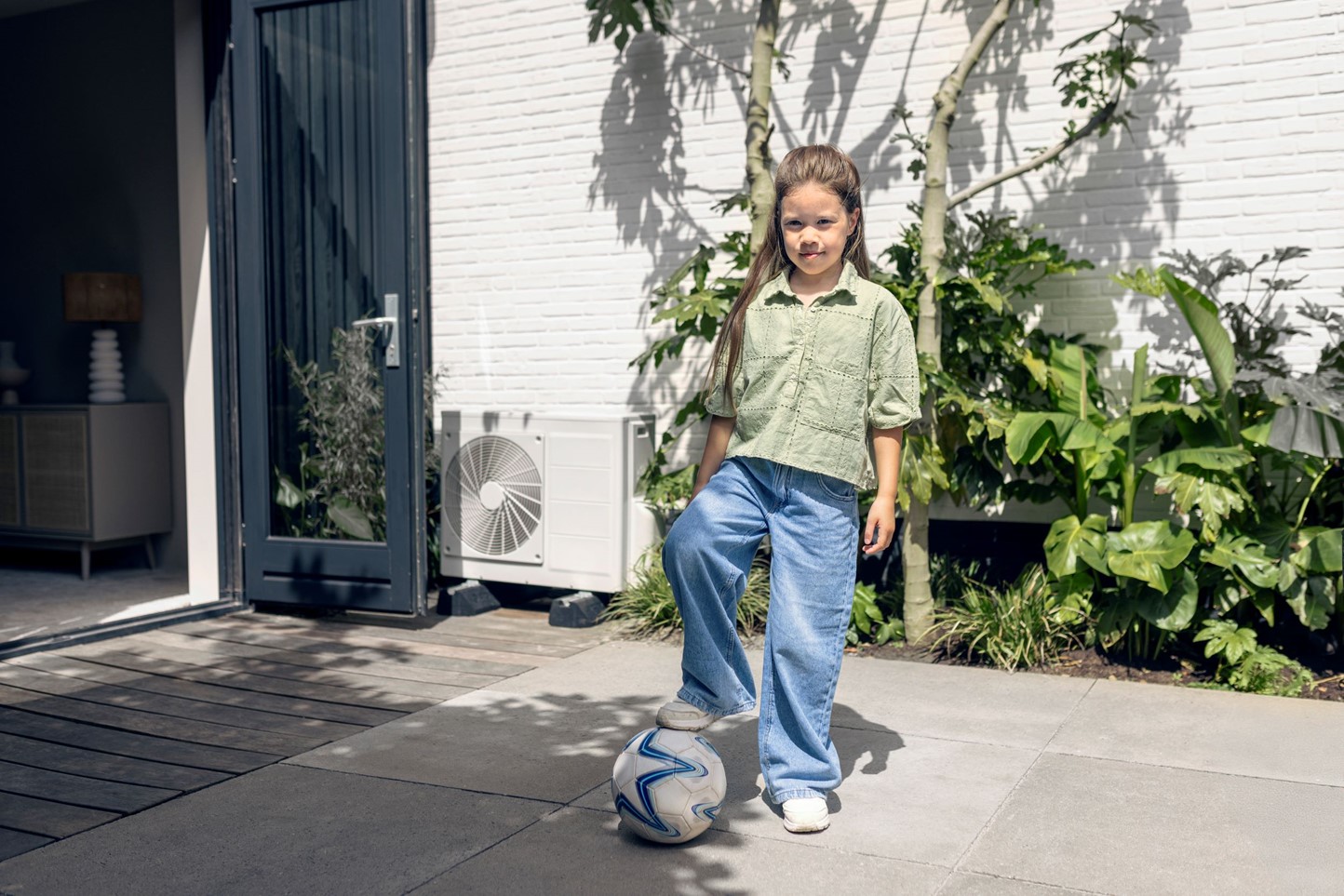 Meisje met voetbal bij warmtepomp