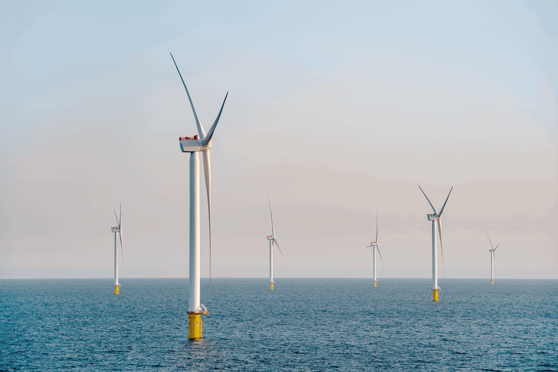 Windmolens op zee tegen een ondergaande zon