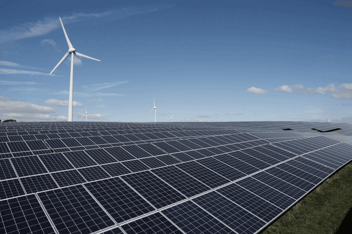 Rijen met zonnepanelen met op de achtergrond een windmolen