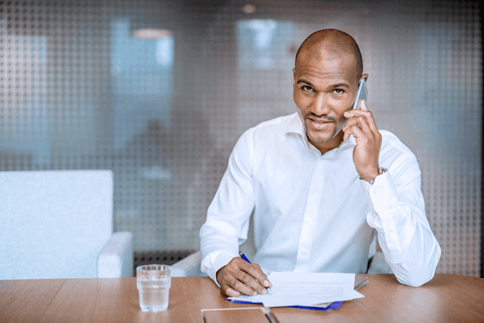 Man aan de telefoon achter een bureau