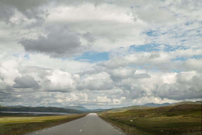 Wolken boven een landschap met een weg en bergen