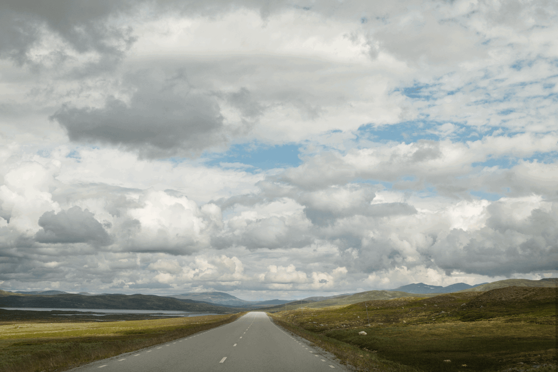 Wolken boven een landschap met een weg en bergen