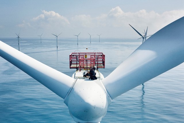 Mannen bovenop een windmolen die windenergie produceert