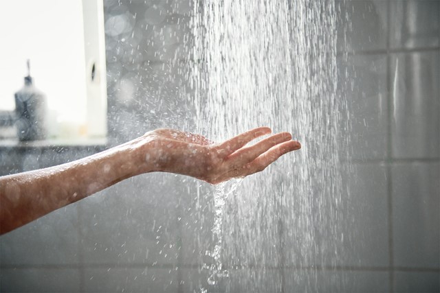 Vrouw in badjas zet de douche aan