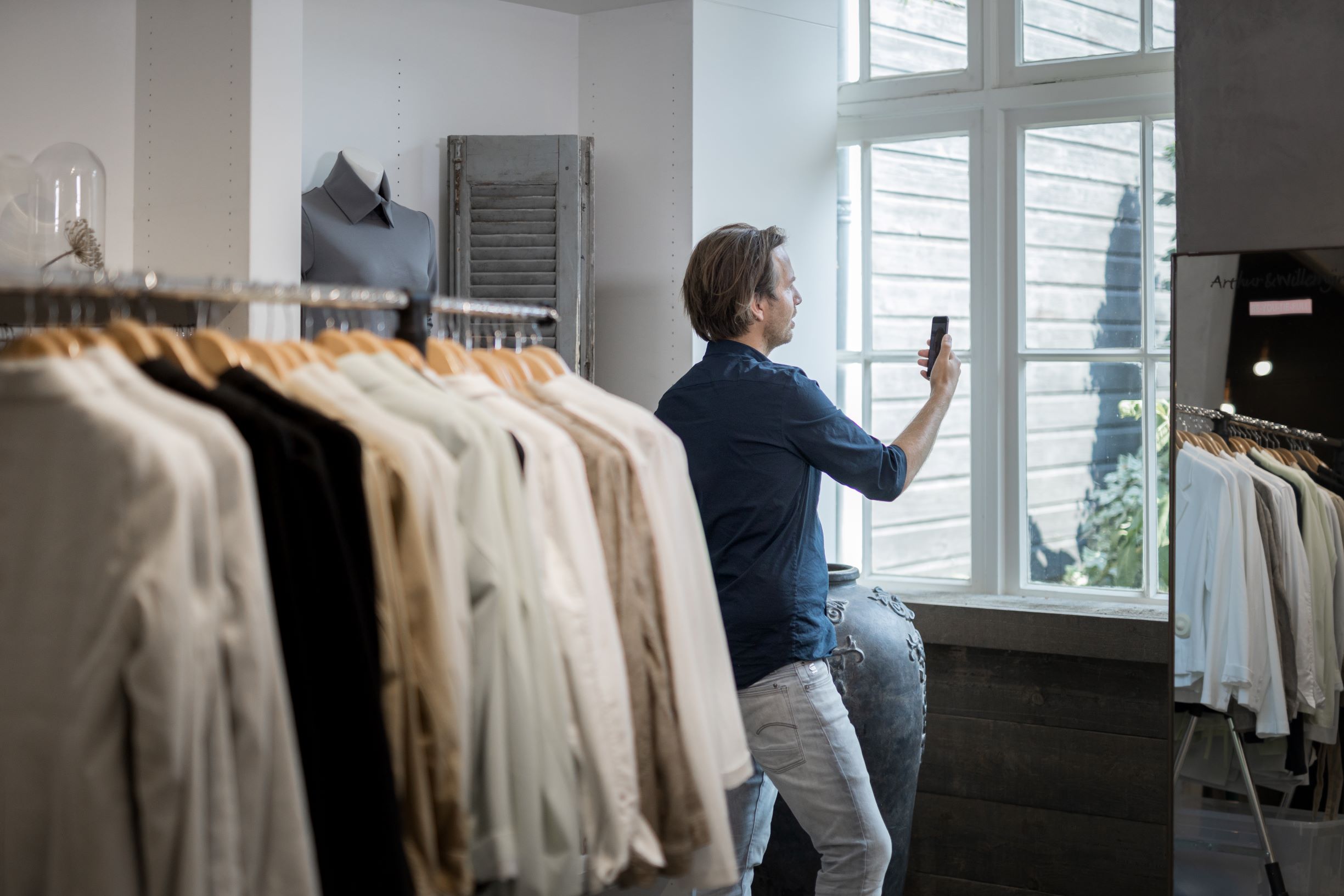 Een ondernemer met een eigen winkel videobelt tussen de kledingrekken over mkb energie mogelijkheden