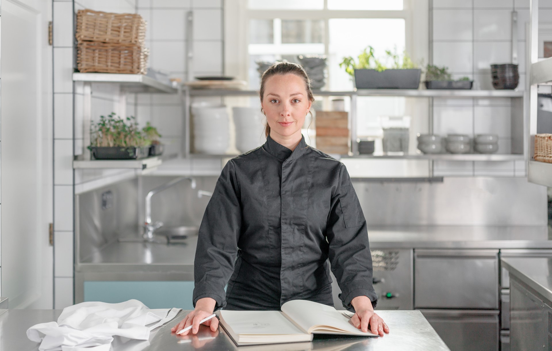 Een vrouw staat in de keuken van horeca en kijkt in de camera
